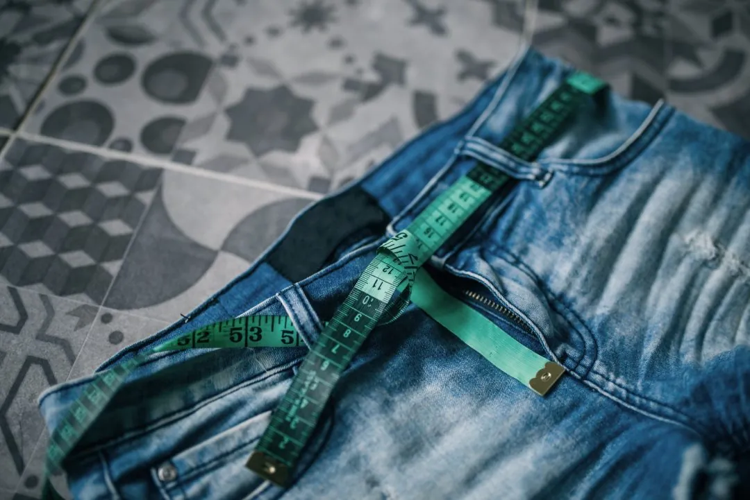 Fita métrica sobre calça jeans e balança