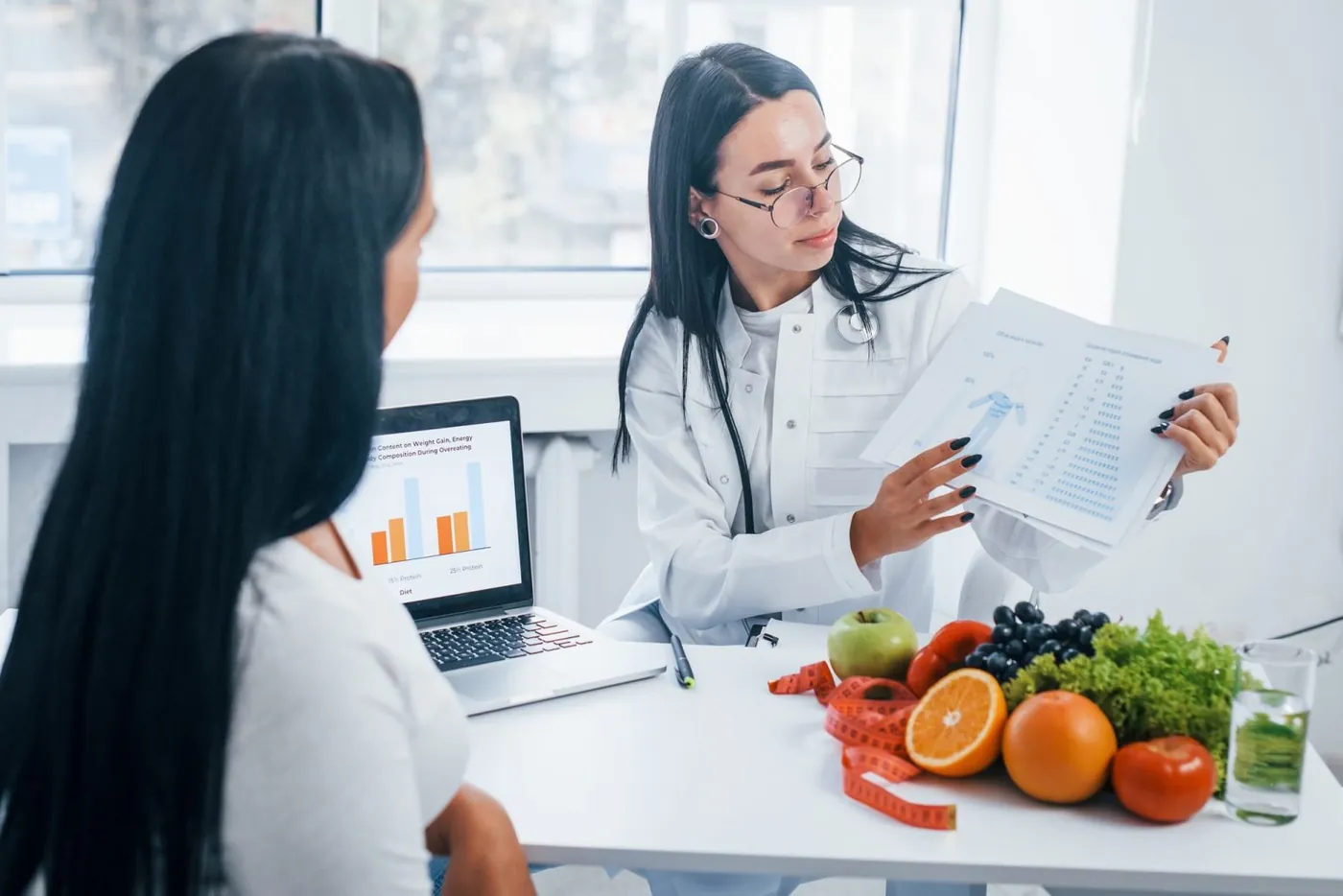 Nutricionista sorridente atendendo com laptop e alimentos saudáveis